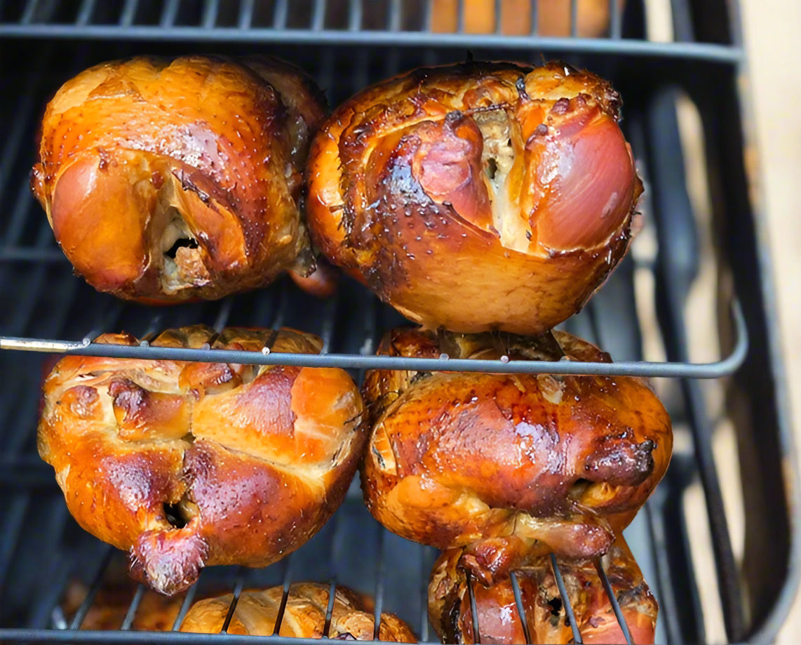 Chicken knuckles being grilled on a barbecue oven.